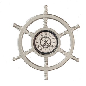 Puede incluir: Un reloj de pared de rueda de barco plateado con una esfera negra y números romanos. La esfera del reloj presenta un ancla negra con una cuerda blanca y un diseño de cruz blanca.
