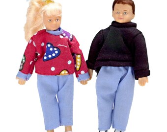 May include: Two dolls, one with blonde hair wearing a red sweater with white polka dots and blue pants, and the other with brown hair wearing a black sweater and blue pants.