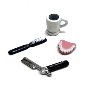May include: A set of miniature bathroom accessories, including a white toothbrush, a black razor, a pink denture, and a white ceramic cup.