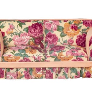 May include: A floral patterned sofa with a pink and cream color scheme. The sofa has a ruffled skirt and rolled arms.