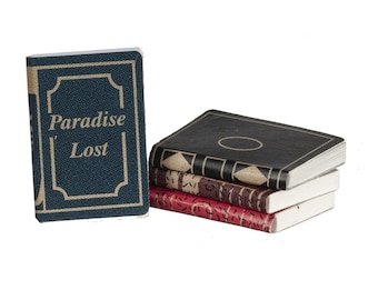 May include: A stack of miniature books with a blue cover book that reads "Paradise Lost". The books have various colors, including black, red, and brown, with gold and white accents. The books are stacked on top of each other.