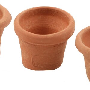 May include: Three small, unglazed terracotta pots. Each pot has a flared rim and a cylindrical body. The pots are a warm, earthy brown colour, and are likely used for planting small plants or succulents.