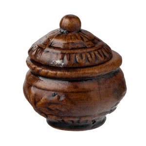 May include: A small, brown ceramic pot with a lid. The pot has a decorative design and a rounded shape.