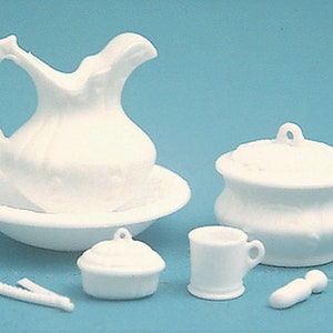 Op de afbeelding: Een witte porseleinen badkamerset met een kan, een waskom, een chamberpot, een mok en een pot met deksel. De set is gemaakt van wit porselein en heeft een vintage stijl.