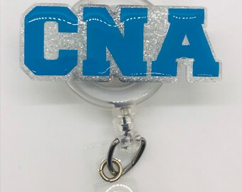 May include: A silver glitter badge reel with a blue "CNA" lettering. The badge reel has a clear plastic retractable cord and a metal clip.