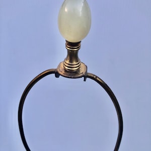 Puede incluir: Un remate de l&aacute;mpara vintage con una parte superior p&aacute;lida en forma de huevo. El remate est&aacute; montado sobre una base de lat&oacute;n con un marco de metal curvado. El dise&ntilde;o es simple y elegante, adecuado para una l&aacute;mpara cl&aacute;sica o antigua.