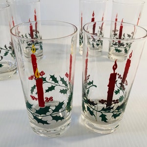 Peut inclure: Ensemble de verres &agrave; boire transparents avec un motif de bougie de No&euml;l. Chaque verre pr&eacute;sente une bougie rouge avec une flamme jaune, du houx et des baies. Parfait pour les f&ecirc;tes de fin d'ann&eacute;e.