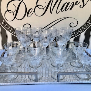 May include: A set of 10 clear glass stemmed drinking glasses with etched designs on a silver tray with a crocodile pattern. The tray has a silver border.