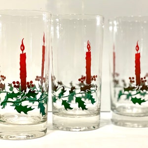 Peut inclure: Ensemble de verres transparents avec un motif de bougie de No&euml;l. Chaque verre pr&eacute;sente une longue bougie rouge avec une flamme, des feuilles de houx vertes et des baies rouges. Id&eacute;al pour les boissons de f&ecirc;te.