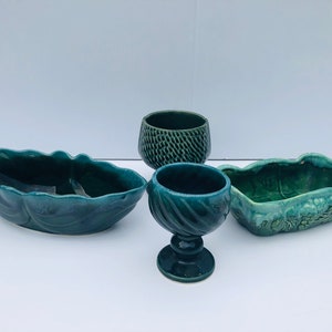 Puede incluir: Cuatro macetas de cerámica verde en diferentes formas y tamaños. Las macetas están todas esmaltadas en un color verde oscuro y tienen una variedad de texturas.