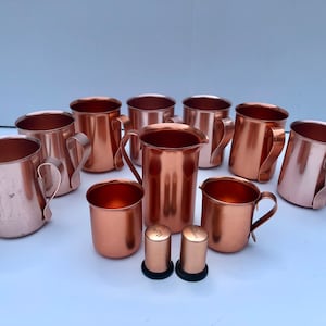 May include: A set of ten copper mugs and two copper salt and pepper shakers. The mugs have a hammered finish and are perfect for serving Moscow Mules or other cocktails.