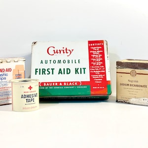 May include: A vintage first aid kit with the text "Curity Automobile First Aid Kit" on the front. The kit is green, red, and white. There are three other vintage tins: a white tin with the text "Band-Aid Plastic Strips", a white tin with the text "Red Cross Adhesive Tape", and a white tin with the text "Squibb Sodium Bicarbonate".