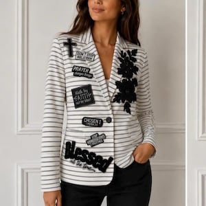 May include: A white blazer with thin horizontal gray stripes, featuring black embroidered floral appliqués on the left lapel and various black rectangular patches on the right side with text including Don't Stop Believin, Prayer, Faith, and Blessed.