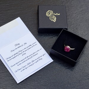 May include: A red ruby ring in a black ring box with a white card that reads "Ruby is the birthstone for July. The fiery and captivating Ruby is a stone of nobility, considered the most magnificent of all gems. The queen of gems and the stone of kings. Accounts tell us it surpassed all other precious stones in value and exceeded even that of the Diamond. The Chinese Emperor Kublai Khan was said to have offered an entire city in exchange for a single Ruby."