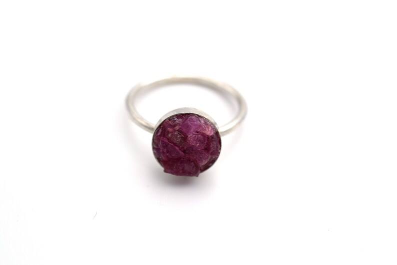 May include: A silver ring with a round, pink, and purple gemstone.