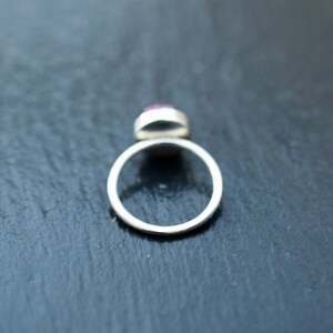 May include: A silver ring with a pink gemstone set in the center.