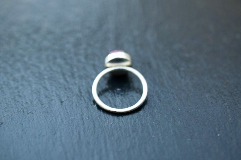 May include: A silver ring with a pink gemstone set in the center.