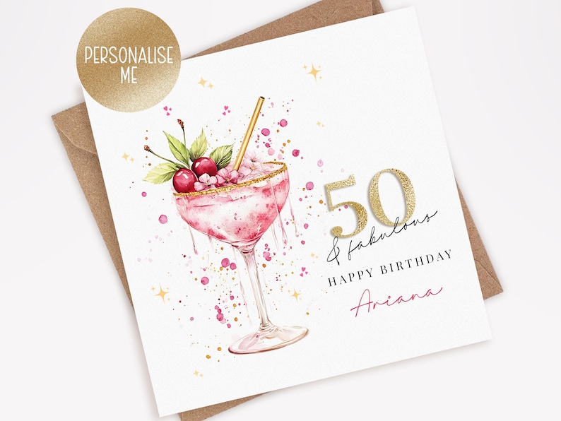May include: A birthday card with a watercolor illustration of a pink cocktail with cherries and a gold straw. The card says "50 & fabulous" and "Happy Birthday Ariana". A gold sticker says "Personalise Me".