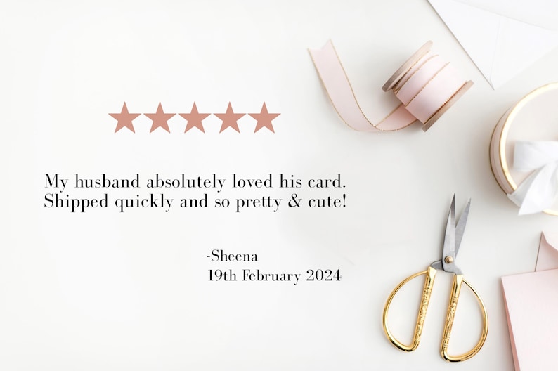 May include: A flat lay featuring a customer review with five star ratings. The text reads, "My husband absolutely loved his card." Gold scissors, a pink ribbon, and a small gift box are also visible.