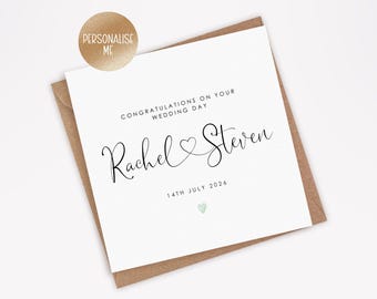 Puede incluir: Una tarjeta de boda blanca con los nombres "Rachel & Steven" en escritura elegante, un símbolo de corazón y la fecha "14 de julio de 2026". La tarjeta está sobre un sobre marrón, con una pegatina dorada que dice "Personalízame".