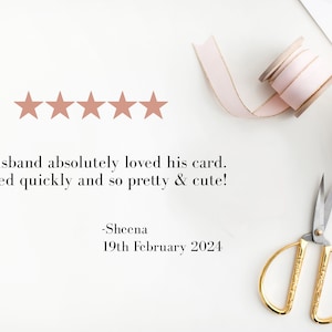 May include: Five gold stars with a review that reads "My husband absolutely loved his card. Shipped quickly and so pretty & cute! -Sheena 19th February 2024". The image also shows a pink ribbon, a spool of pink ribbon, a pair of gold scissors, and a white gift box with a pink ribbon.