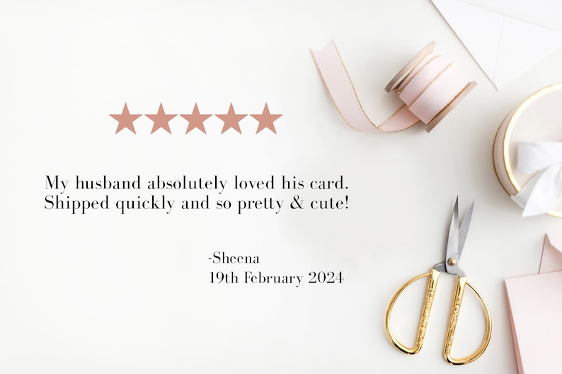 May include: Five gold stars with a review that reads "My husband absolutely loved his card. Shipped quickly and so pretty & cute! -Sheena 19th February 2024". The image also shows a pink ribbon, a spool of pink ribbon, a pair of gold scissors, and a white gift box with a pink ribbon.