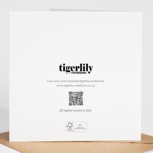 May include: A white greeting card with the text "tigerlily creations" in black. Below the text are website addresses and a QR code. The card is on a brown envelope.