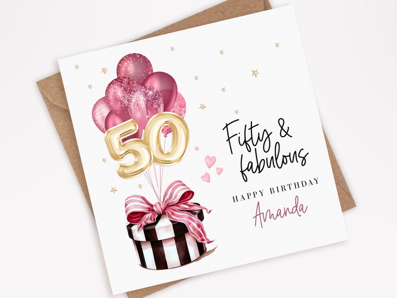 Puede incluir: Una tarjeta de cumplea&ntilde;os con un sobre marr&oacute;n. La tarjeta presenta un grupo de globos rosas, globos dorados con el n&uacute;mero 50 y una caja de regalo con un lazo rosa. El texto dice "Fifty & fabulous" y "Happy Birthday Amanda".