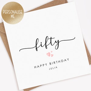 May include: A white card with black text that says "fifty" in cursive with two pink hearts above the text. Below the text is "Happy Birthday Julia".