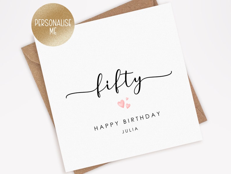 May include: A white card with black text that says "fifty" in cursive with two pink hearts above the text. Below the text is "Happy Birthday Julia".