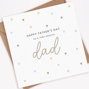 May include: A white card with a light brown envelope. The card has a light brown background with a scattered pattern of small blue, peach, and brown hearts. The card reads "Happy Father's Day to a very special dad" in black text.