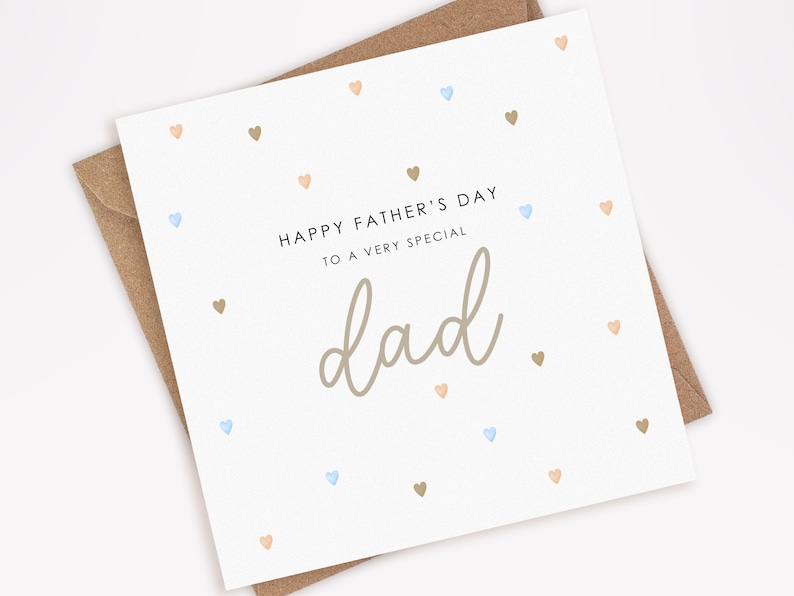 May include: A white card with a light brown envelope. The card has a light brown background with a scattered pattern of small blue, peach, and brown hearts. The card reads "Happy Father's Day to a very special dad" in black text.