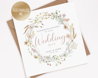 May include: A white wedding card with a floral wreath design. The text reads "Congratulations on your Wedding Day Jane & John 14.07.24".