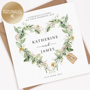 May include: A white wedding card with a floral heart design. The card features the names "Katherine and James" and the date "15th June 2024". The words "Congratulations on your wedding day" are at the top. A small tag reads "with love".