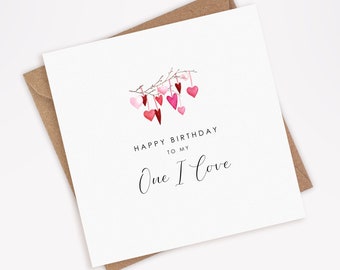 May include: A white card with a watercolor illustration of pink and red hearts hanging from a branch. The text "Happy Birthday to my One I Love" is printed on the card.