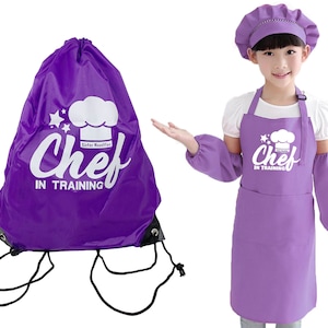 May include: A purple drawstring backpack and a matching chef's outfit. The backpack features the text "Chef in Training" with a chef's hat graphic. The outfit includes a chef's hat, apron, and arm sleeves, also with the "Chef in Training" design.