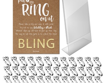 May include: A bridal shower game set with a brown card that reads "put a RING on it" and "BLING" in gold lettering. Includes a clear acrylic sign holder and numerous silver rings with clear gemstones.