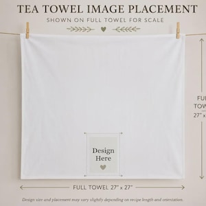 May include: A square white tea towel hanging from a clothesline with two wooden clips. The towel features a central rectangular area labeled Design Here with a small heart icon. Text indicates the full towel measures 27 inches by 27 inches.