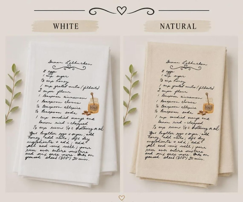 May include: Two folded kitchen towels, one white and one natural beige, each printed with a black cursive German Lebkuchen recipe. The text includes ingredients like eggs, sugar, honey, nuts, flour, spices, and instructions, accompanied by a small honey jar illustration.