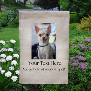 May include: A beige burlap garden flag with a color photo of a small dog. The flag has the text "Your Text Here! Add a photo of your own pet!" printed in black. The flag is hanging on a black metal stand.