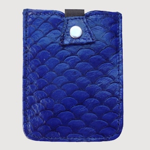 May include: A cobalt blue leather card holder with a scale-like texture. The rectangular case has a flap secured by a silver snap and a black elastic loop. The design is a solid, vibrant blue.