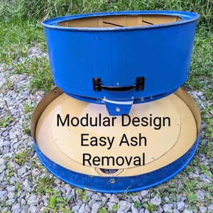 Puede incluir: Un componente de brasero de metal azul con un asa negra y una base circular color canela. El texto Modular Design Easy Ash Removal est&aacute; impreso en la base. La estructura presenta una secci&oacute;n superior cil&iacute;ndrica y una bandeja inferior plana.