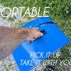 Puede incluir: Un contenedor de pl&aacute;stico azul brillante de forma semicircular con un asa negra sujeta con herrajes met&aacute;licos. El texto PORTABLE est&aacute; impreso en la parte superior, mientras que PICK IT UP TAKE IT WITH YOU aparece en la parte inferior.