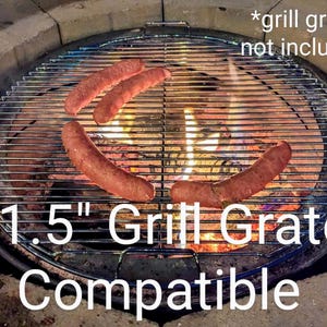 Puede incluir: Una rejilla de parrilla circular de metal colocada sobre un pozo de fuego con cuatro salchichas marrones cocin&aacute;ndose en la superficie. El texto 54,6 cm Grill Grate Compatible y *grill grate not included es visible sobre las barras.