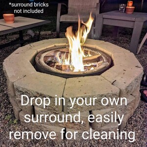 Puede incluir: Un inserto circular de metal para fogata con un fuego de le&ntilde;a encendido en su interior, rodeado por un anillo de bloques de hormig&oacute;n gris claro. El texto en la imagen dice: *surround bricks not included, Drop in your own surround, easily remove for cleaning.