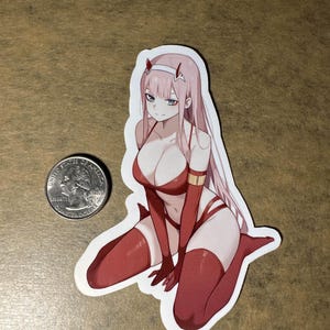 May include: A sticker featuring an anime character with pink hair, wearing a red and white outfit with a gold belt. The character is kneeling with their hands on their knees.
