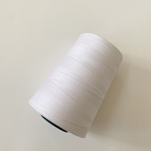 May include: A white spool of thread with a green plastic centre.