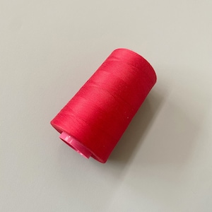 May include: A spool of bright red thread.