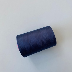 May include: A spool of dark blue thread.