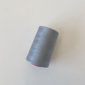 May include: A spool of silver grey thread.